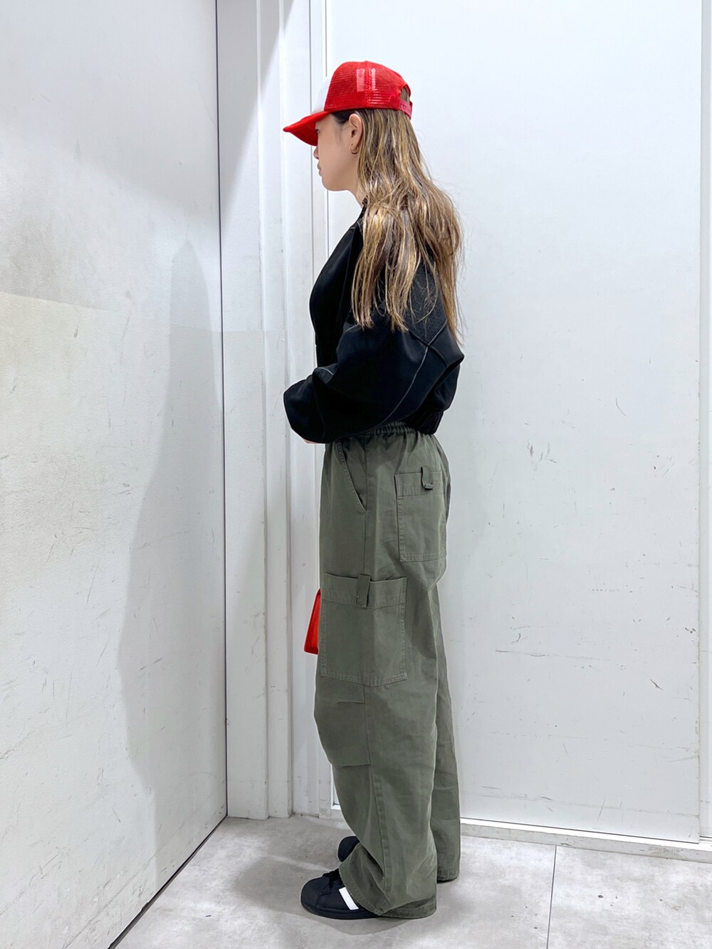 グリーン系のその他パンツ、ブラック系のブルゾン、レッド系のショルダーバッグを着用したレディースの秋コーディネートの2枚目の写真