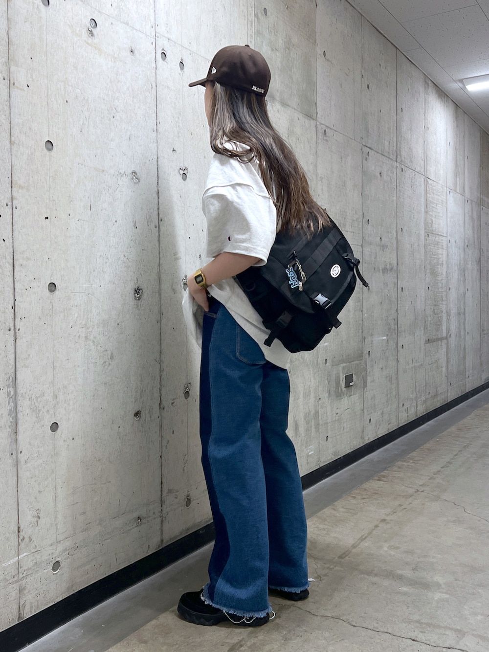 ブラック系のショルダーバッグ、グレー系のTシャツ/カットソー、ブルー系のデニムパンツを着用したレディースの春コーディネートの2枚目の写真