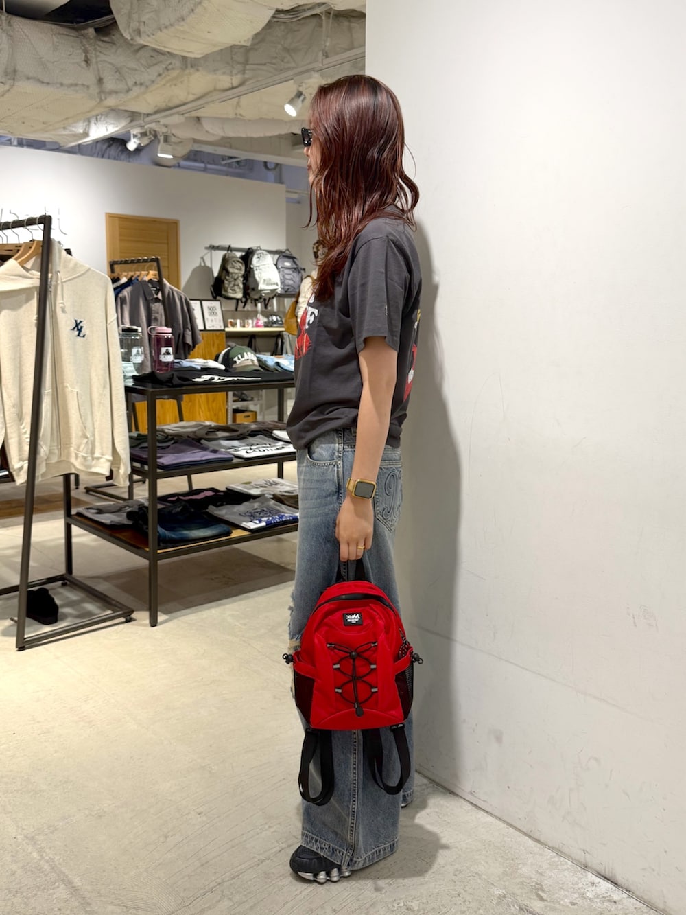 ブルー系のデニムパンツ、ブラック系のTシャツ/カットソー、レッド系のバックパック/リュックを着用したレディースの夏コーディネートの2枚目の写真