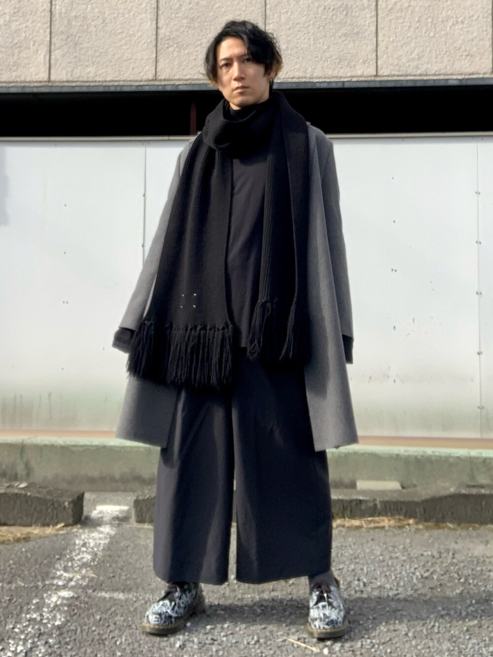 グレー系のチェスターコート、ブラック系のTシャツ/カットソー、ブラック系のスラックスを着用したメンズの冬コーディネートの4枚目の写真