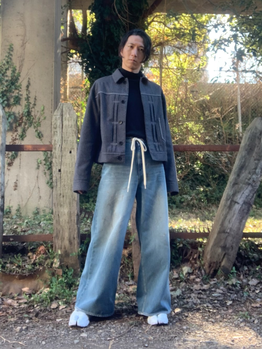 ホワイト系のスニーカー、ブラック系のニット/セーター、ブルー系のデニムパンツを着用したメンズの冬コーディネートの2枚目の写真