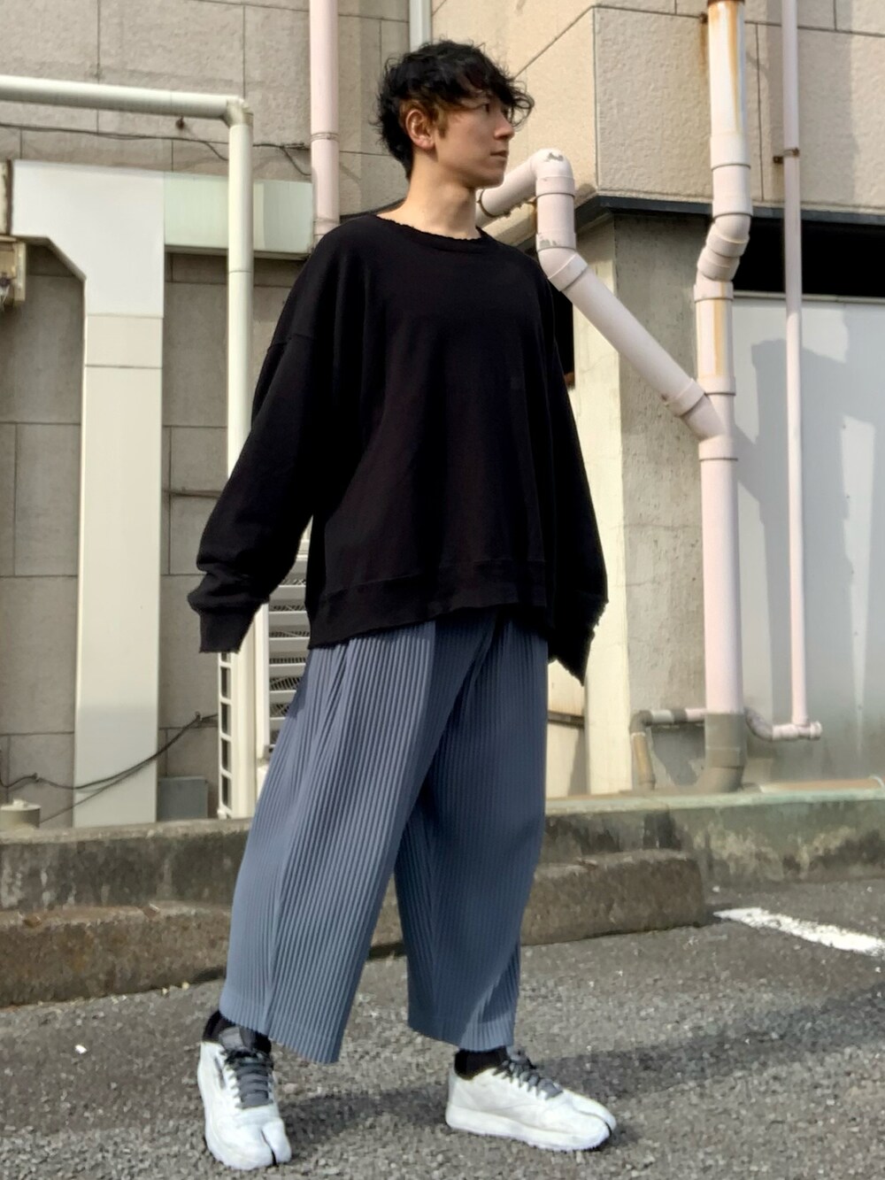 ブラック系のスウェット、ブルー系のパンツ、ホワイト系のスニーカーを着用したメンズの秋コーディネートの2枚目の写真