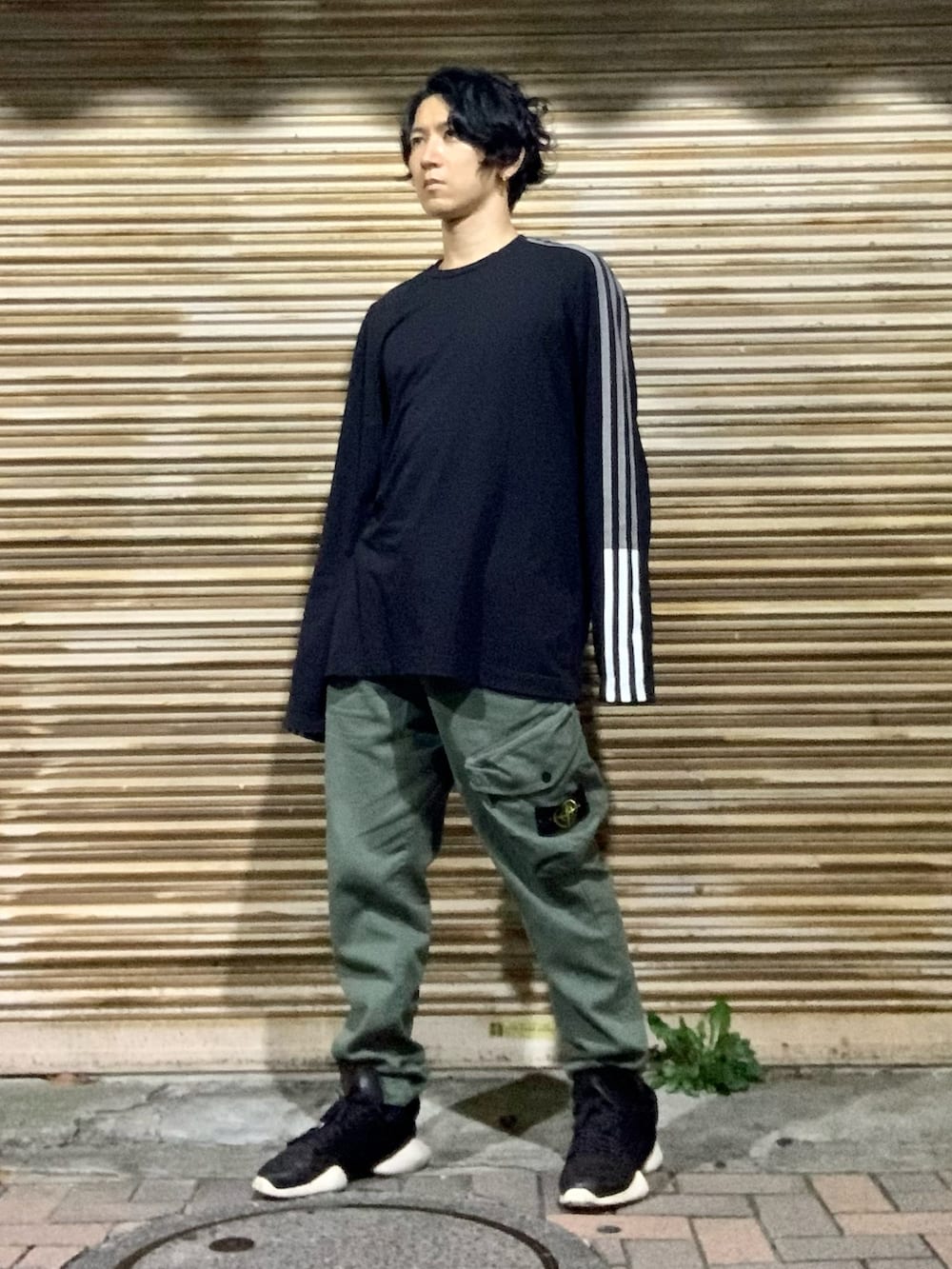 ブラック系のTシャツ/カットソー、グリーン系のカーゴパンツ、ブラック系のスニーカーを着用したメンズの秋コーディネートの4枚目の写真