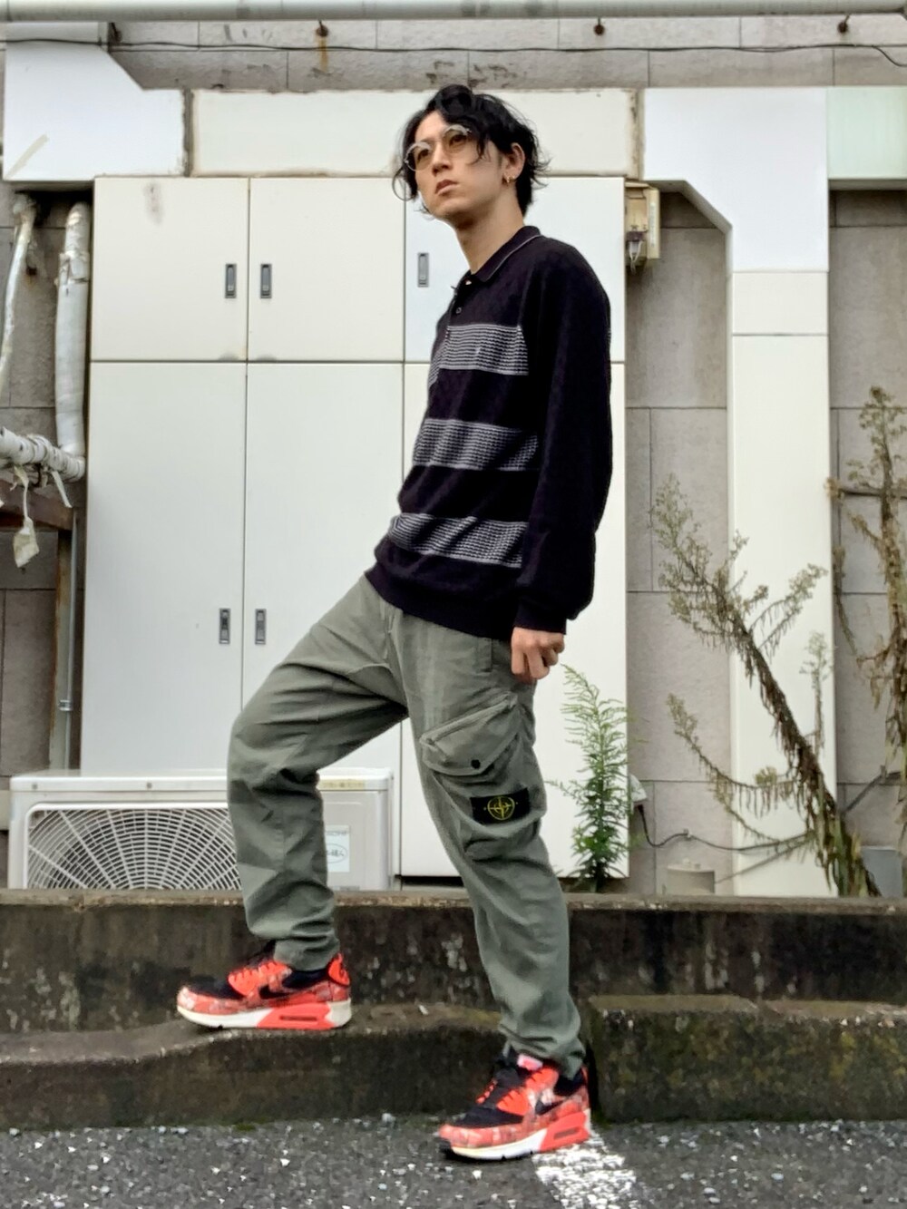 グリーン系のカーゴパンツ、レッド系のスニーカー、ブラック系のポロシャツを着用したメンズの秋コーディネートの2枚目の写真