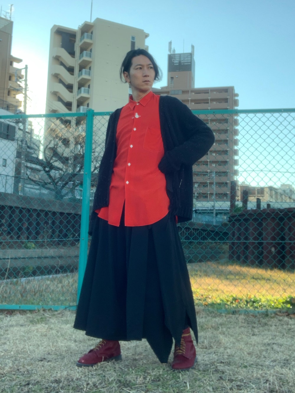 レッド系のブーツ、ブラック系のスラックス、ブラック系のカーディガン/ボレロを着用したメンズの冬コーディネートの3枚目の写真