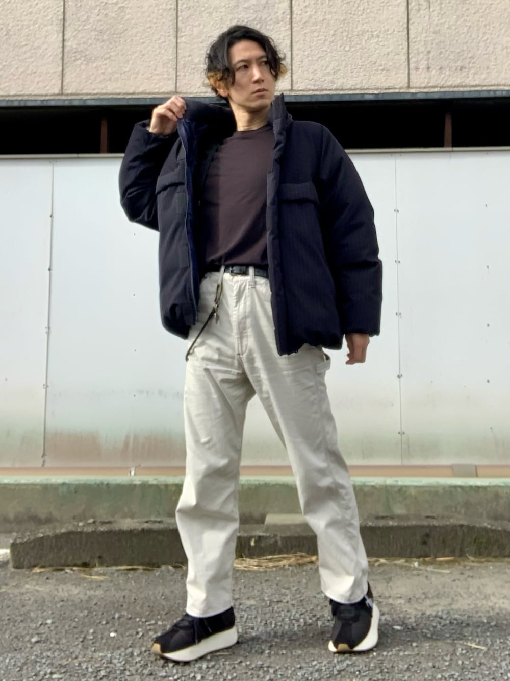 ブラック系のTシャツ/カットソー、ブラック系のダウンジャケット/コート、ホワイト系のチノパンツを着用したメンズの冬コーディネートの2枚目の写真