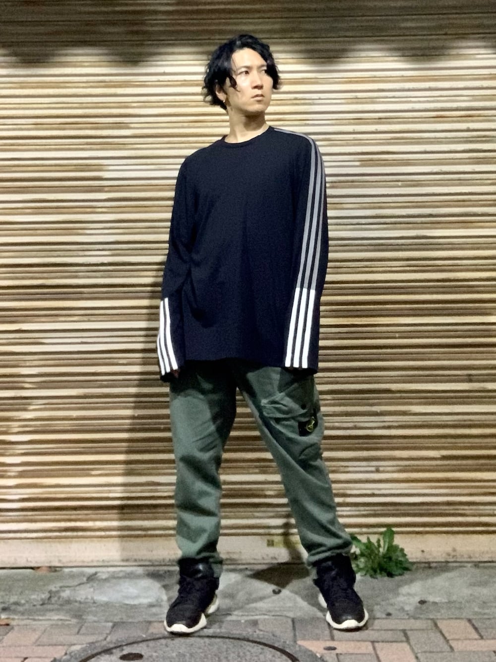 ブラック系のTシャツ/カットソー、グリーン系のカーゴパンツ、ブラック系のスニーカーを着用したメンズの秋コーディネートの2枚目の写真