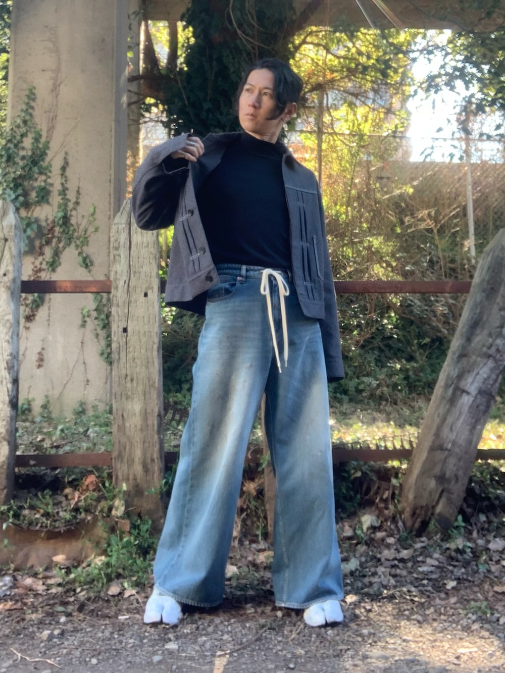 ホワイト系のスニーカー、ブラック系のニット/セーター、ブルー系のデニムパンツを着用したメンズの冬コーディネートの3枚目の写真