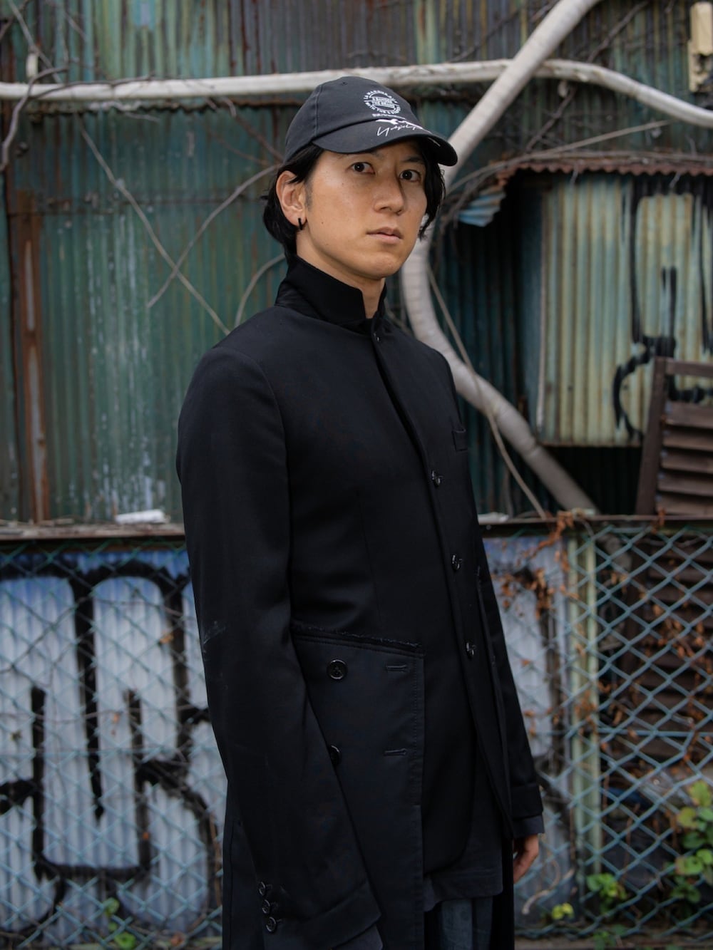 ブラック系のテーラードジャケット、ブラック系のTシャツ/カットソー、グレー系のスラックスを着用したメンズの秋コーディネートの2枚目の写真