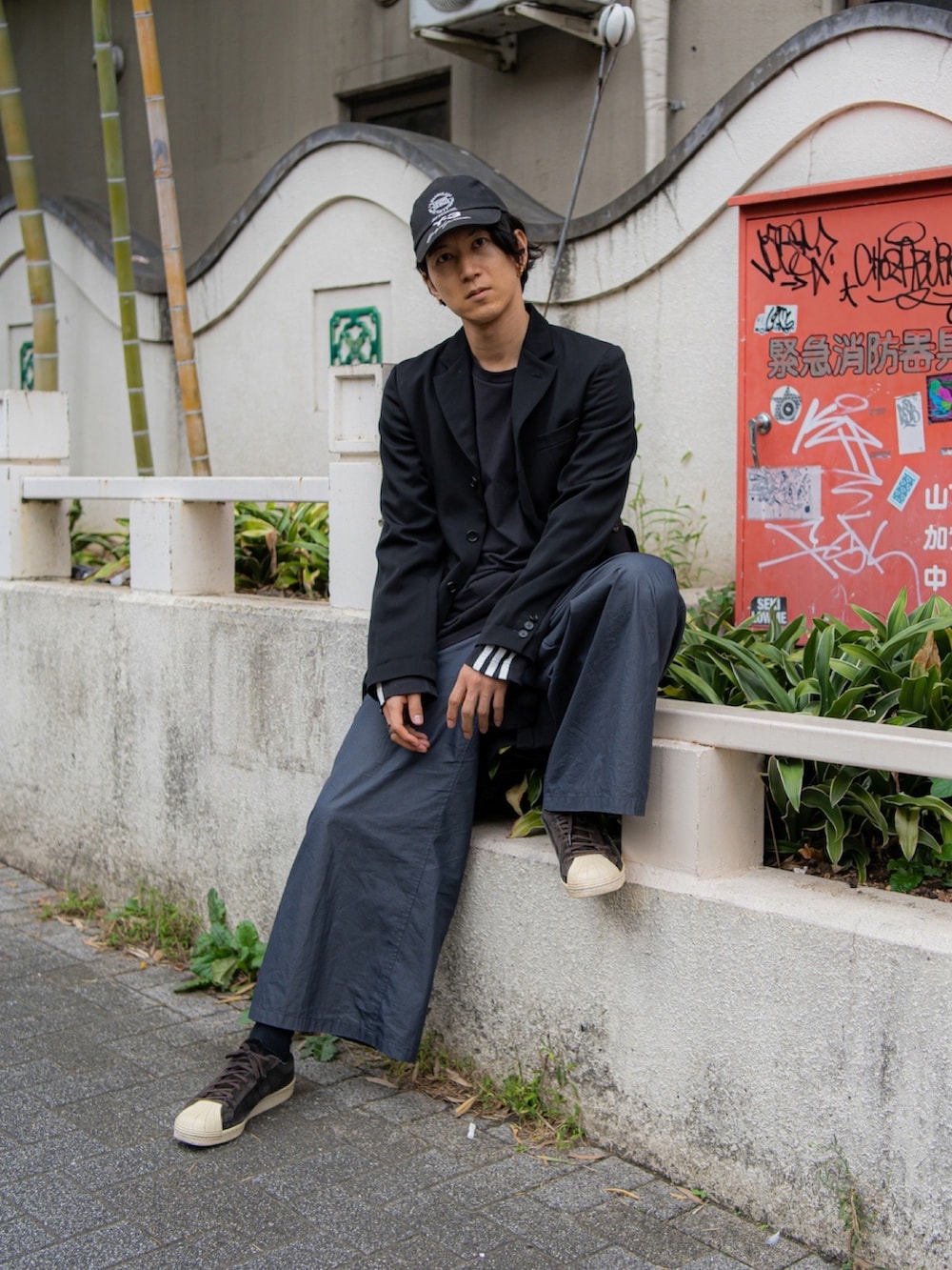 ブラック系のテーラードジャケット、ブラック系のTシャツ/カットソー、グレー系のスラックスを着用したメンズの秋コーディネートの3枚目の写真