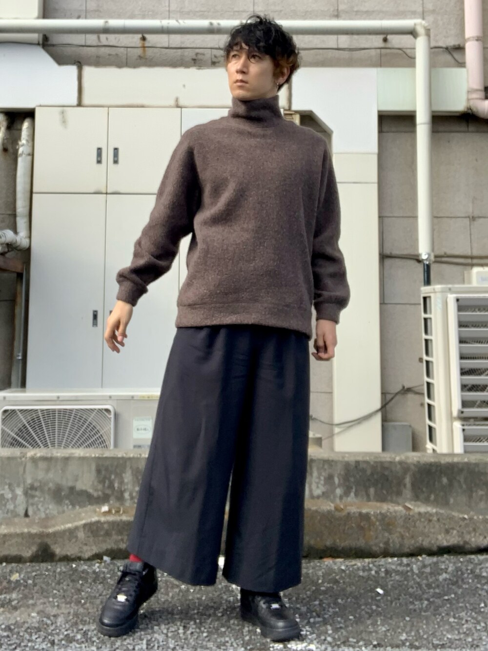 ブラウン系のニット/セーター、ブラック系のスラックス、ブラック系のスニーカーを着用したメンズの秋コーディネートの2枚目の写真