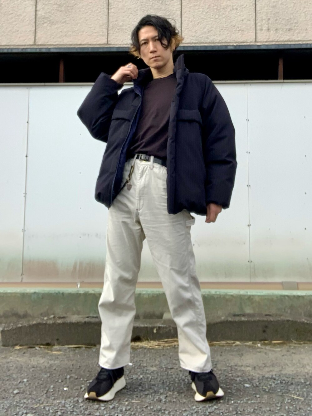 ブラック系のTシャツ/カットソー、ブラック系のダウンジャケット/コート、ホワイト系のチノパンツを着用したメンズの冬コーディネートの4枚目の写真