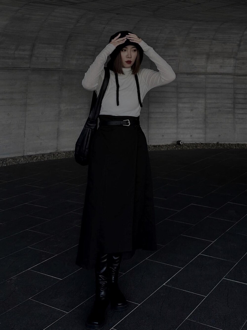 ホワイト系のトップス、ブラック系のスカート、ブラック系のブーツを着用したレディースの春コーディネートの2枚目の写真