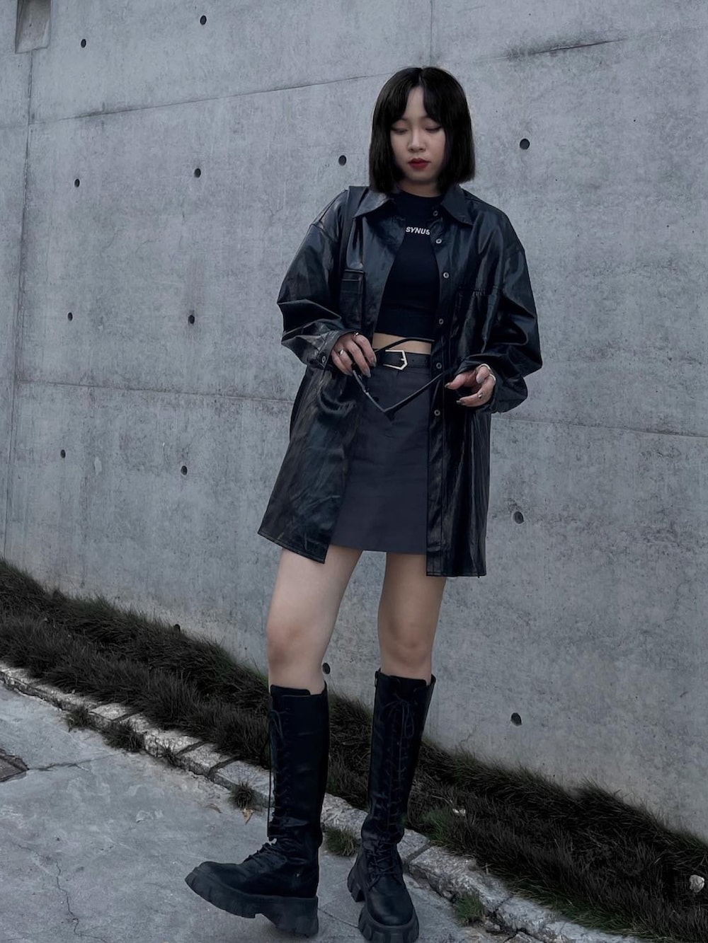 ブラック系のブーツ、ブラック系のジャケット/アウター、グレー系のスカートを着用したレディースの春コーディネートの2枚目の写真