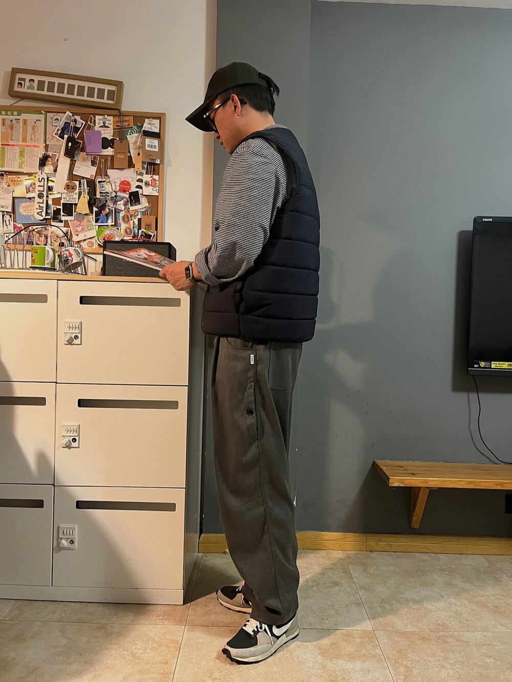 ブラック系のスニーカー、グレー系のスラックス、ブラック系のダウンベストを着用したメンズの春コーディネートの3枚目の写真