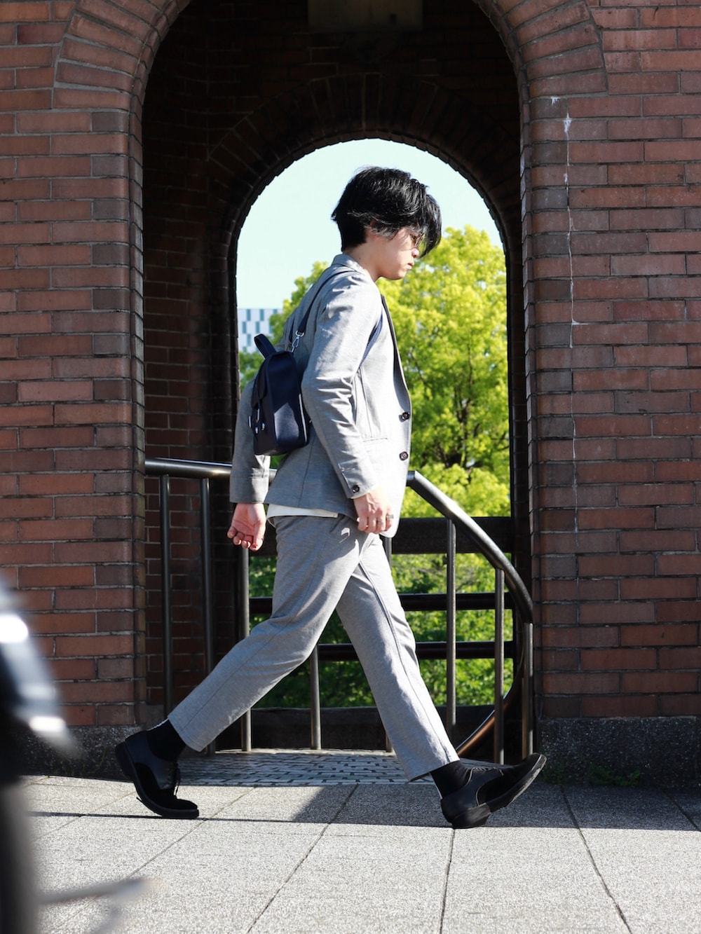 グレー系のテーラードジャケット、ブルー系のニット/セーター、グレー系のその他パンツを着用したメンズの春コーディネートの2枚目の写真