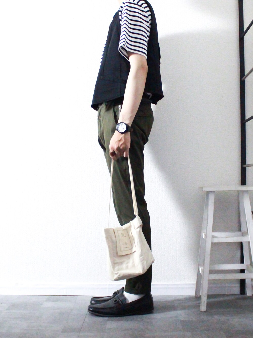 ブラック系のベスト、ホワイト系のTシャツ/カットソー、グリーン系のスラックスを着用したメンズの夏コーディネートの2枚目の写真