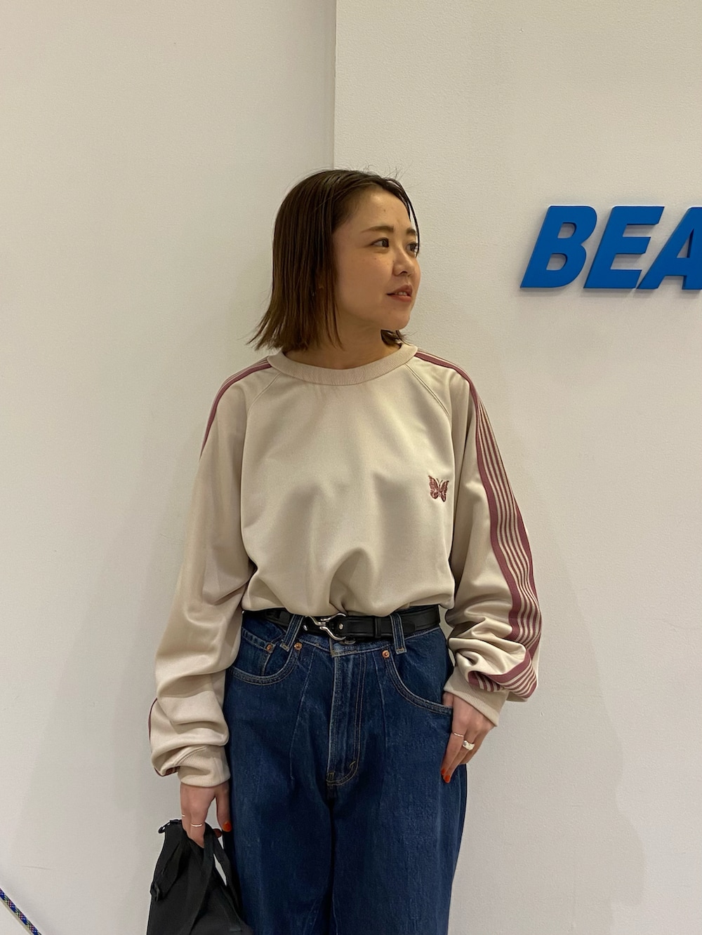 ホワイト系のスニーカー、グレー系のショルダーバッグ、ブラック系のベルトを着用したレディースの冬コーディネートの3枚目の写真