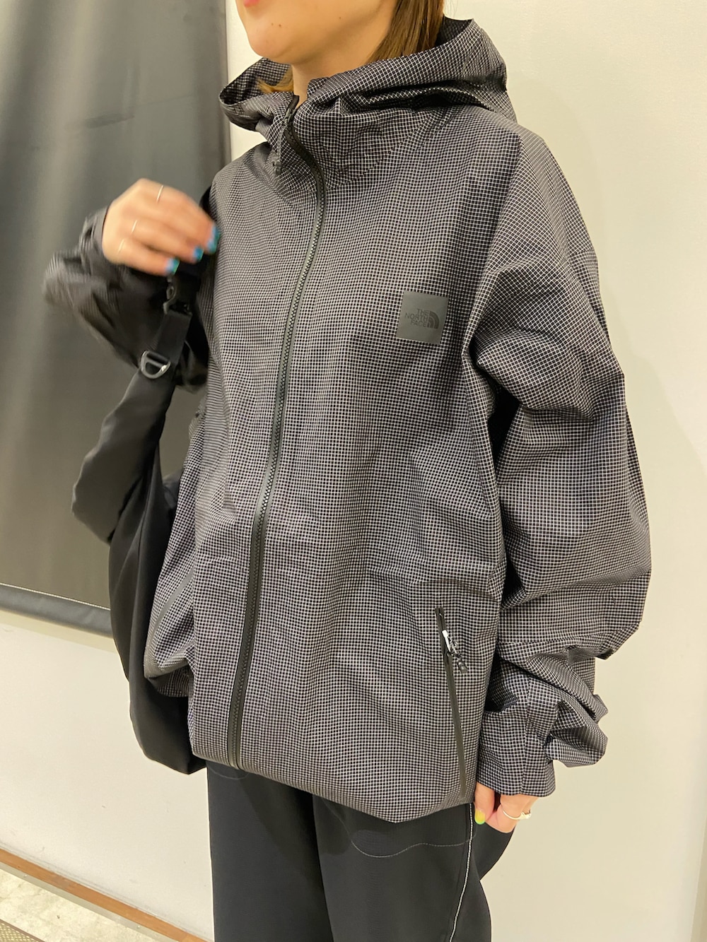 ブラック系のスニーカー、ブラック系のショルダーバッグ、ブラック系のナイロンジャケットを着用したレディースの春コーディネートの4枚目の写真