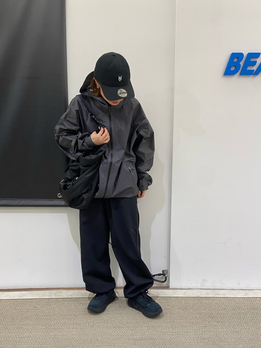 ブラック系のスニーカー、ブラック系のショルダーバッグ、ブラック系のナイロンジャケットを着用したレディースの春コーディネートの2枚目の写真