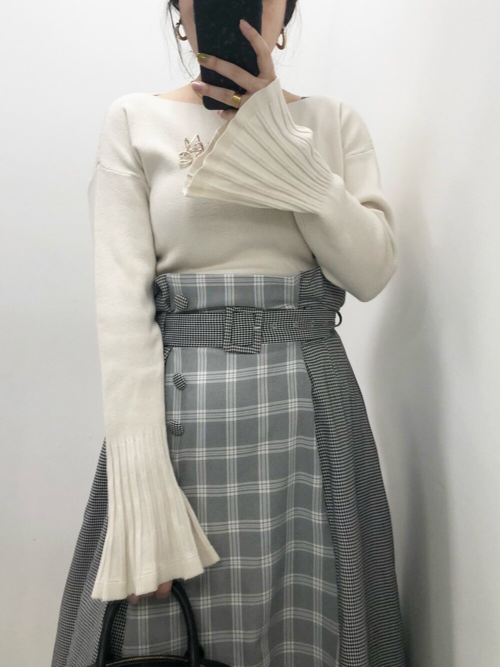 グレー系のスカート、ホワイト系のニット/セーター、ブラック系のボストンバッグを着用したレディースの春コーディネートの2枚目の写真