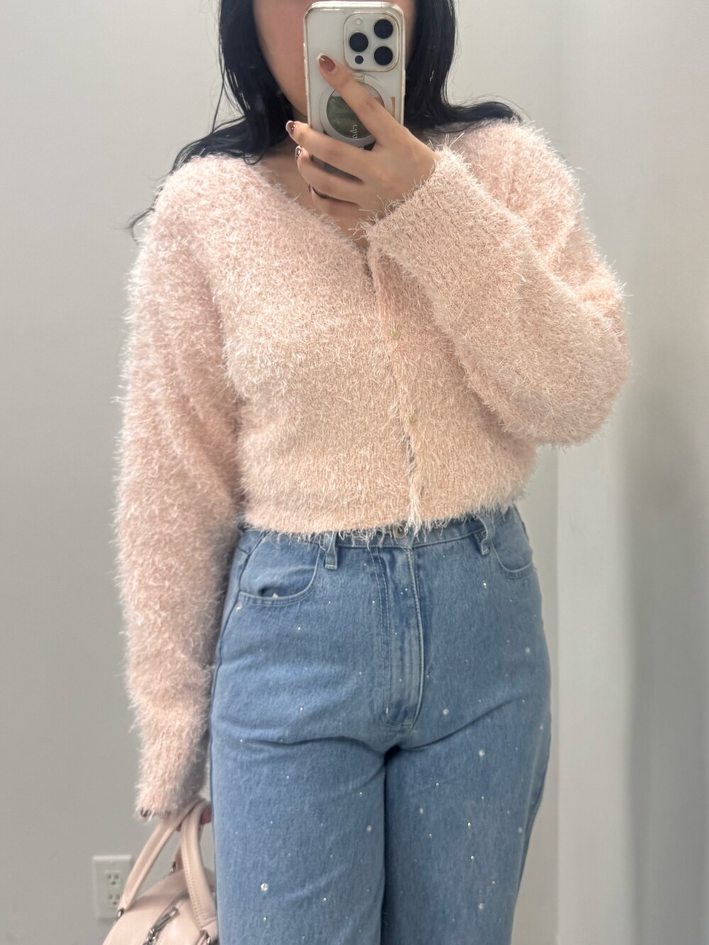 ブルー系のデニムパンツ、ピンク系のカーディガン/ボレロ、ピンク系のハンドバッグを着用したレディースの冬コーディネートの2枚目の写真