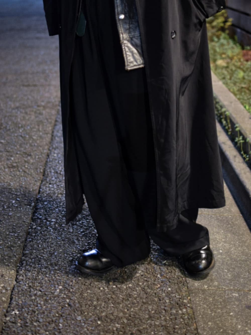 ブラック系のベスト、ブラック系のトレンチコート、ブラック系のスラックスを着用したメンズの春コーディネートの3枚目の写真