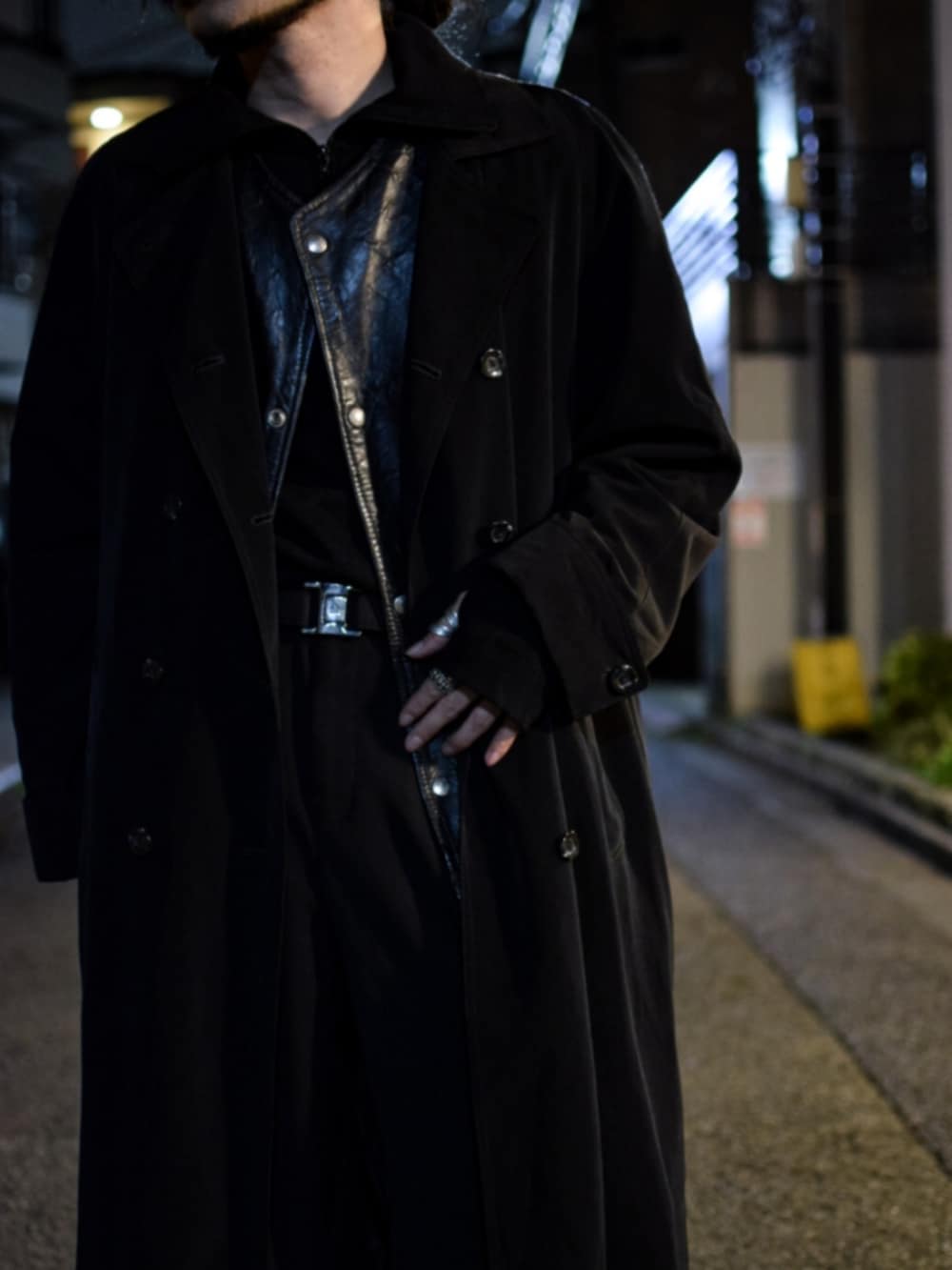 ブラック系のベスト、ブラック系のトレンチコート、ブラック系のスラックスを着用したメンズの春コーディネートの2枚目の写真