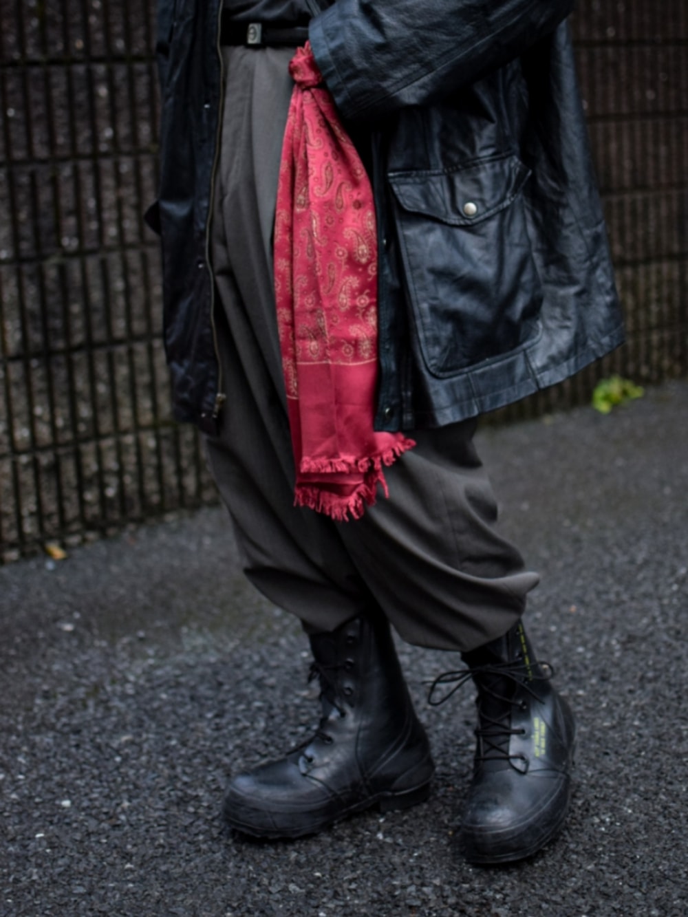 ブラック系のミリタリージャケット、ブラック系のTシャツ/カットソー、ブラウン系のスラックスを着用したメンズの春コーディネートの2枚目の写真