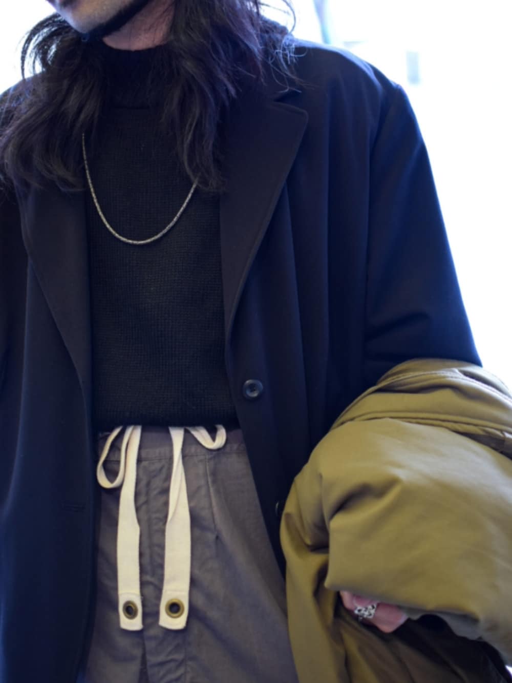 ブラック系のニット/セーター、グリーン系のミリタリージャケット、グレー系のカーゴパンツを着用したメンズの春コーディネートの3枚目の写真