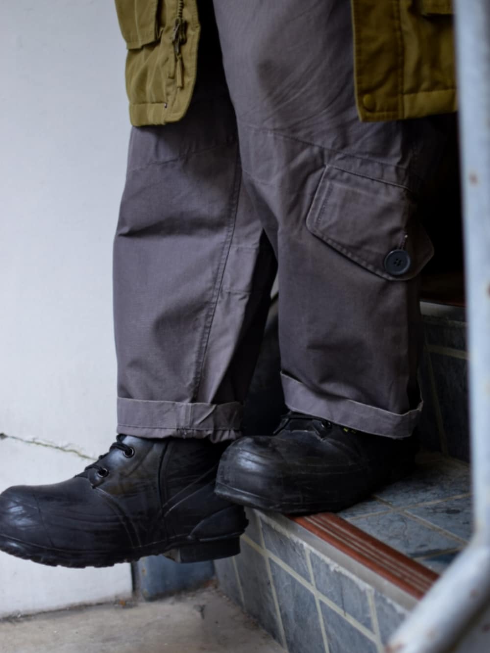 ブラック系のニット/セーター、グリーン系のミリタリージャケット、グレー系のカーゴパンツを着用したメンズの春コーディネートの2枚目の写真