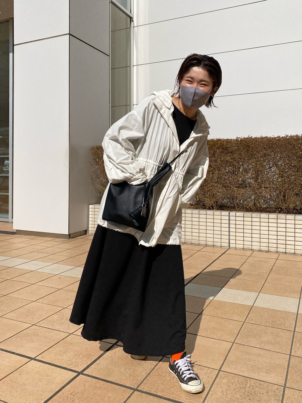 ホワイト系のマウンテンパーカー、ブラック系のワンピースを着用したレディースの春コーディネートの2枚目の写真