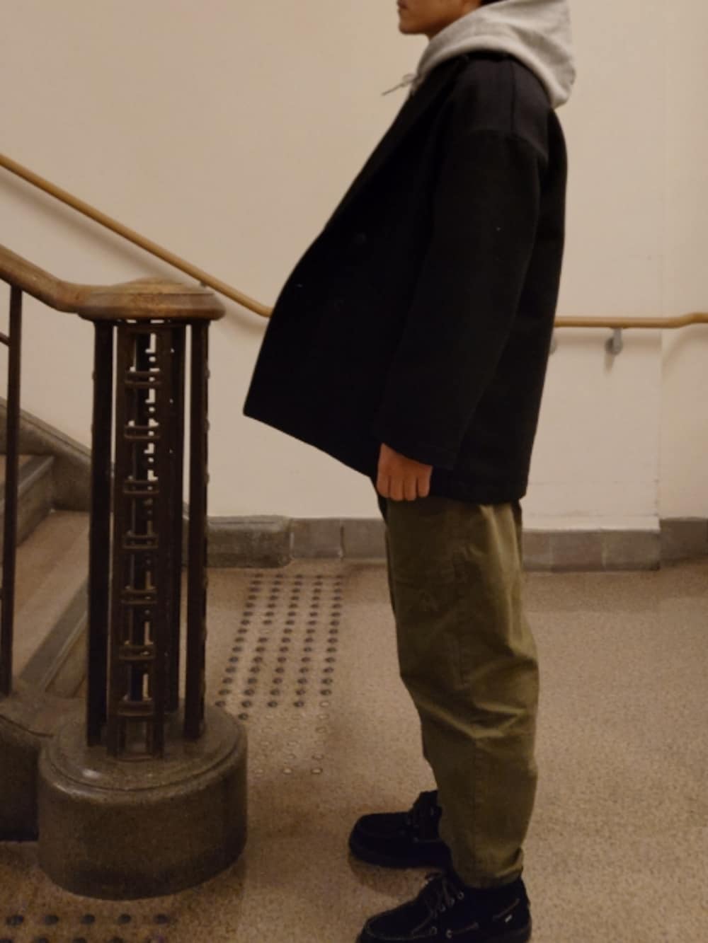 ブラック系のピーコート、グレー系のパーカー、グリーン系のその他パンツを着用したメンズの冬コーディネートの2枚目の写真