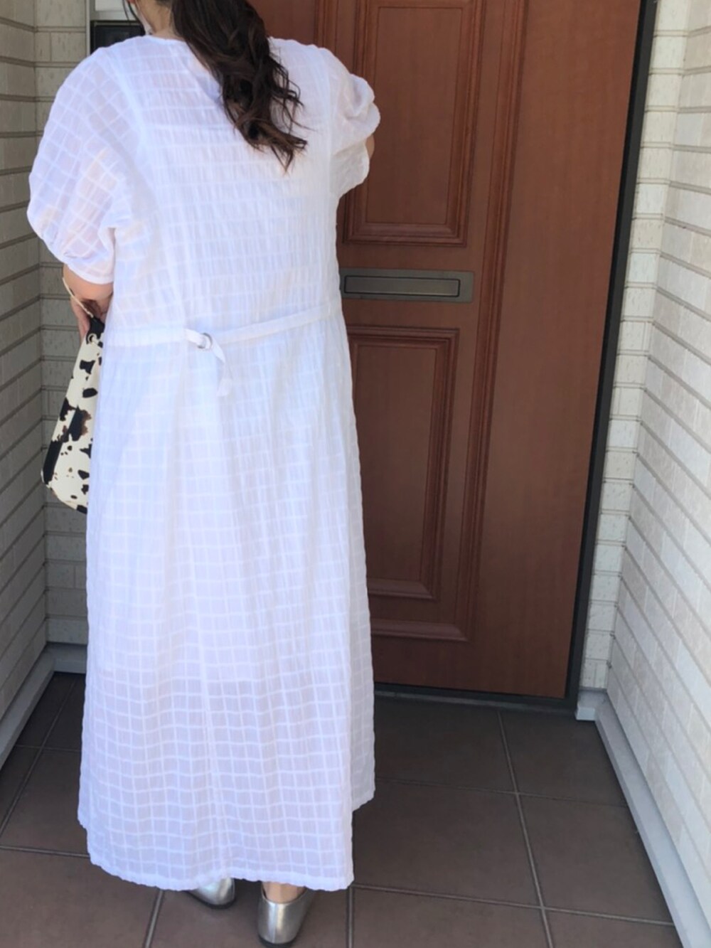 ホワイト系のワンピース、シルバー系のシューズを着用したレディースの春コーディネートの2枚目の写真