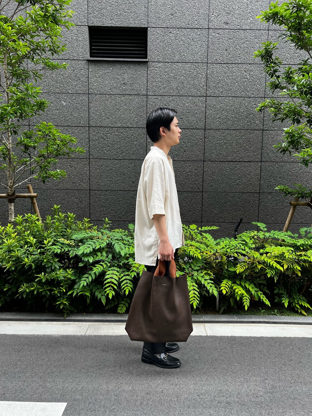 ホワイト系のシャツ/ブラウス、ブラック系のスラックス、ブラウン系のハンドバッグを着用したメンズの夏コーディネートの2枚目の写真