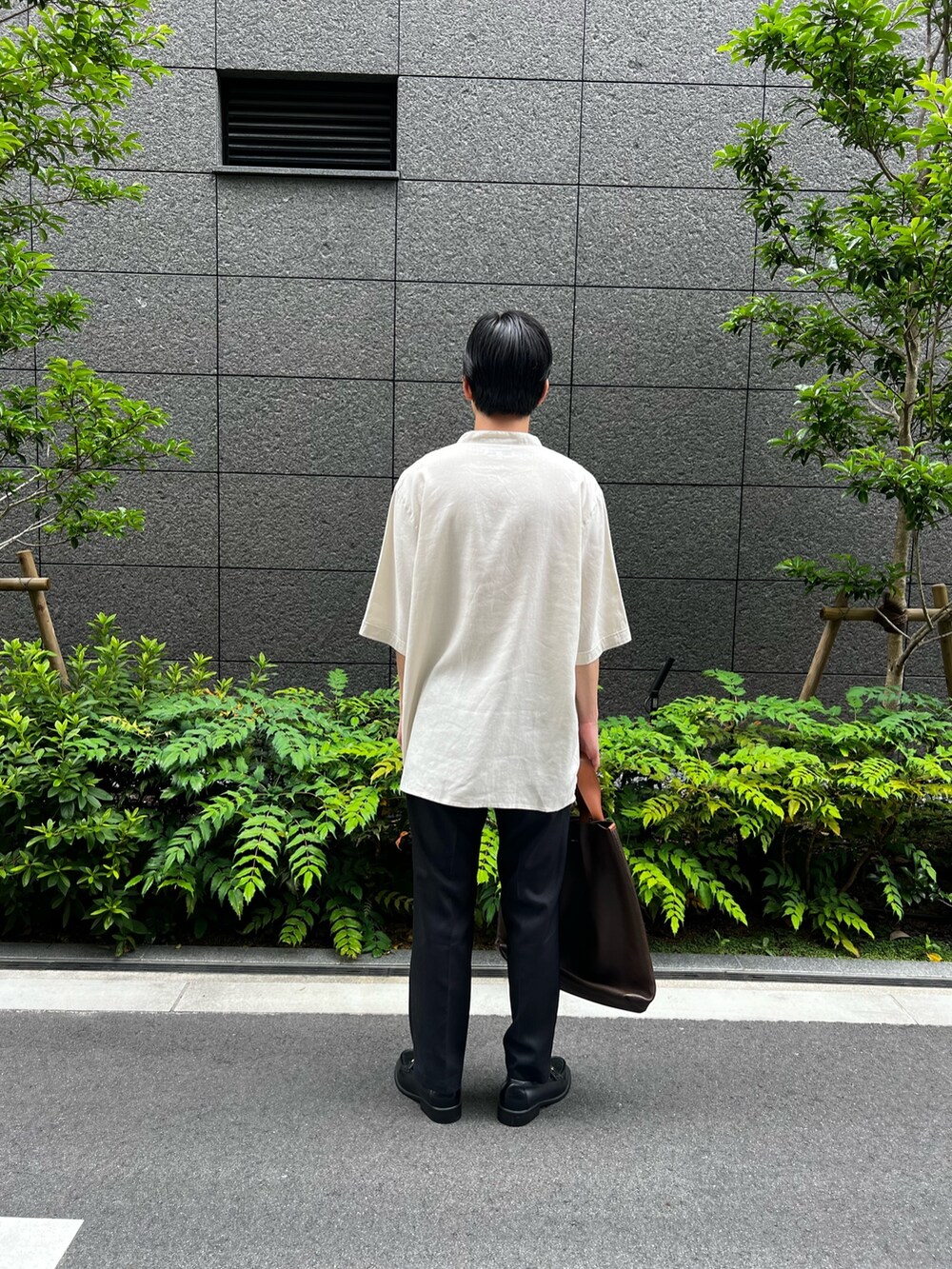ホワイト系のシャツ/ブラウス、ブラック系のスラックス、ブラウン系のハンドバッグを着用したメンズの夏コーディネートの3枚目の写真