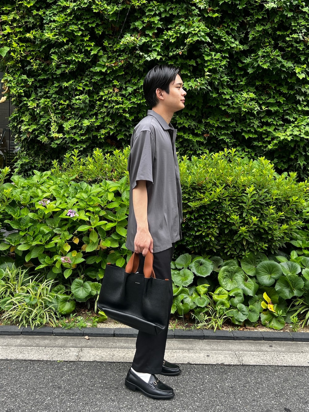 グレー系のシャツ/ブラウス、ブラック系のスラックス、ブラック系のハンドバッグを着用したメンズの夏コーディネートの3枚目の写真
