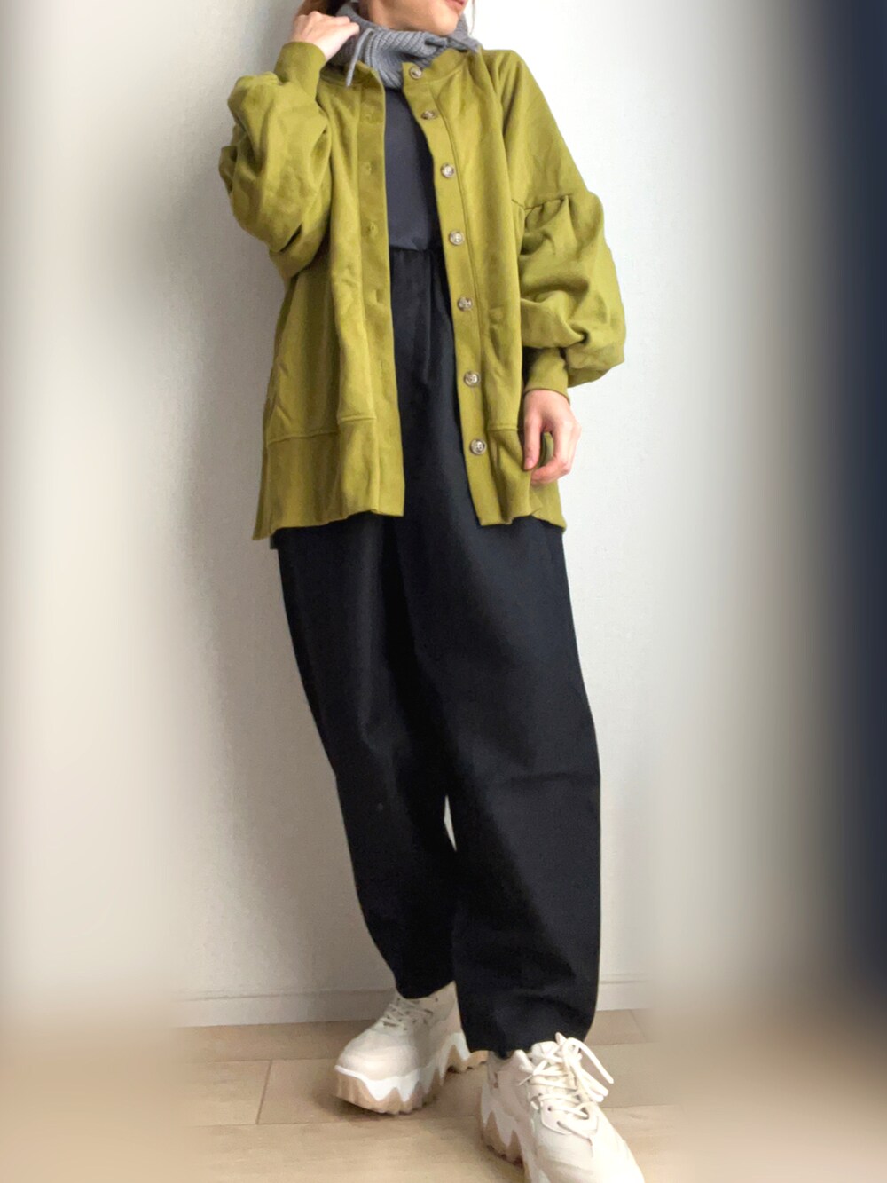 グリーン系のカーディガン/ボレロ、ブラウン系のスラックス、ベージュ系のスニーカーを着用したレディースの秋コーディネートの2枚目の写真