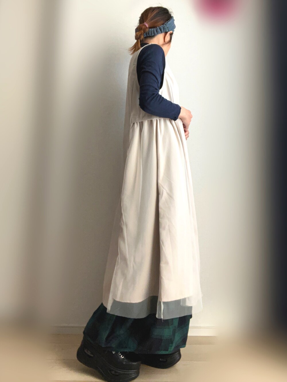 ベージュ系のベスト、グリーン系のスカート、ブラック系のスニーカーを着用したレディースの冬コーディネートの3枚目の写真