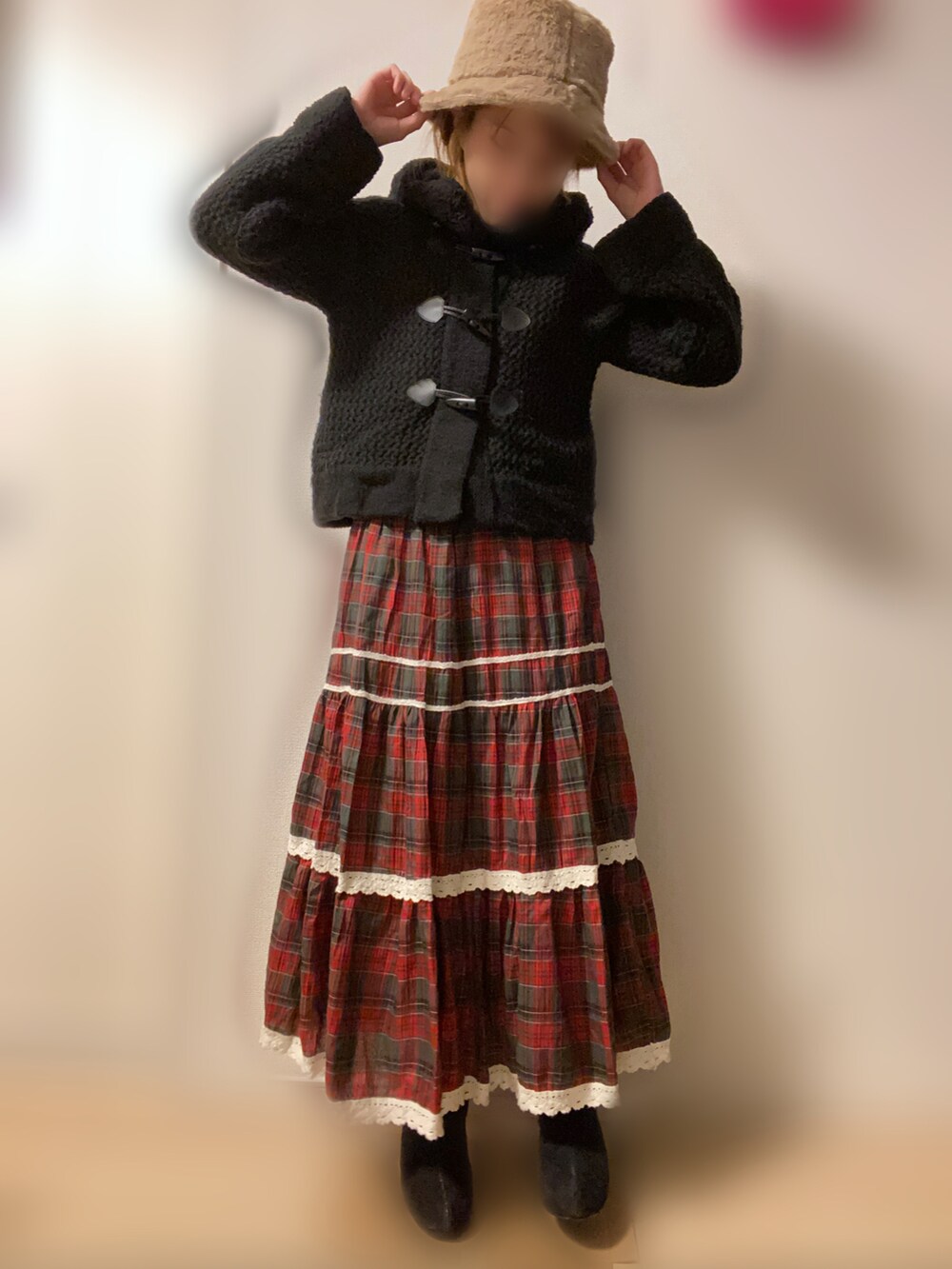 ブラック系のポンチョ、レッド系のスカートを着用したレディースの冬コーディネートの2枚目の写真