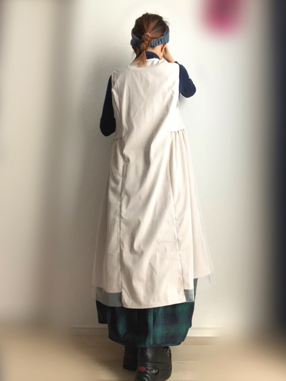 ベージュ系のベスト、グリーン系のスカート、ブラック系のスニーカーを着用したレディースの冬コーディネートの4枚目の写真