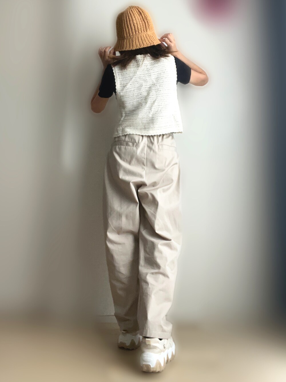 ホワイト系のベスト、ベージュ系のチノパンツ、ベージュ系のスニーカーを着用したレディースの夏コーディネートの2枚目の写真