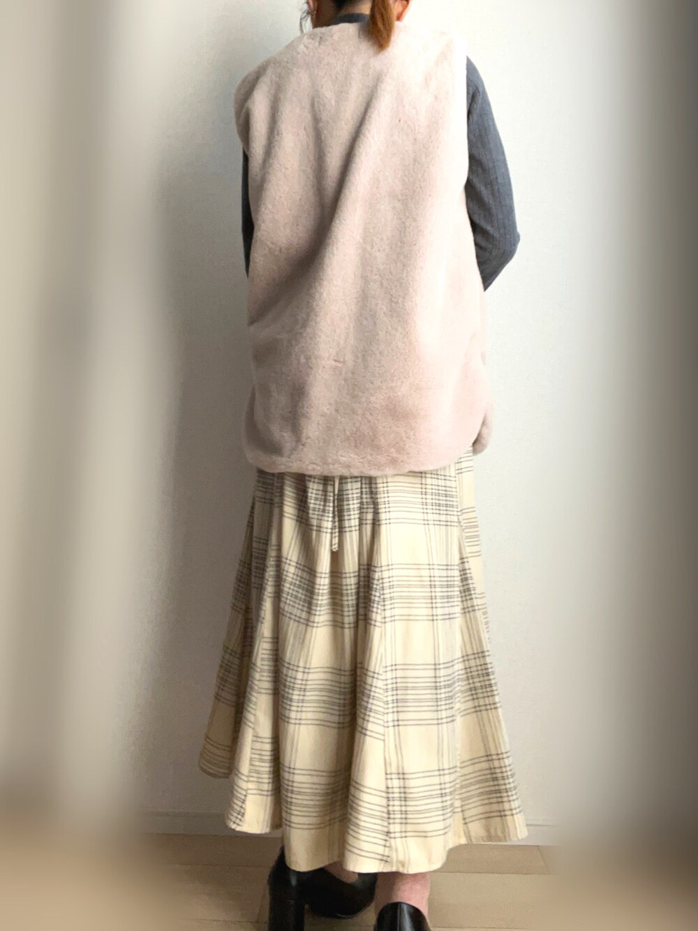 ベージュ系のベスト、ホワイト系のスカートを着用したレディースの冬コーディネートの2枚目の写真