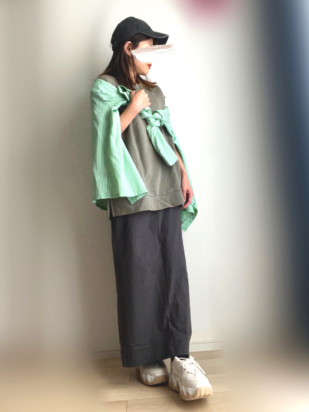 ベージュ系のスニーカー、グレー系のスカート、グリーン系のTシャツ/カットソーを着用したレディースの秋コーディネートの2枚目の写真