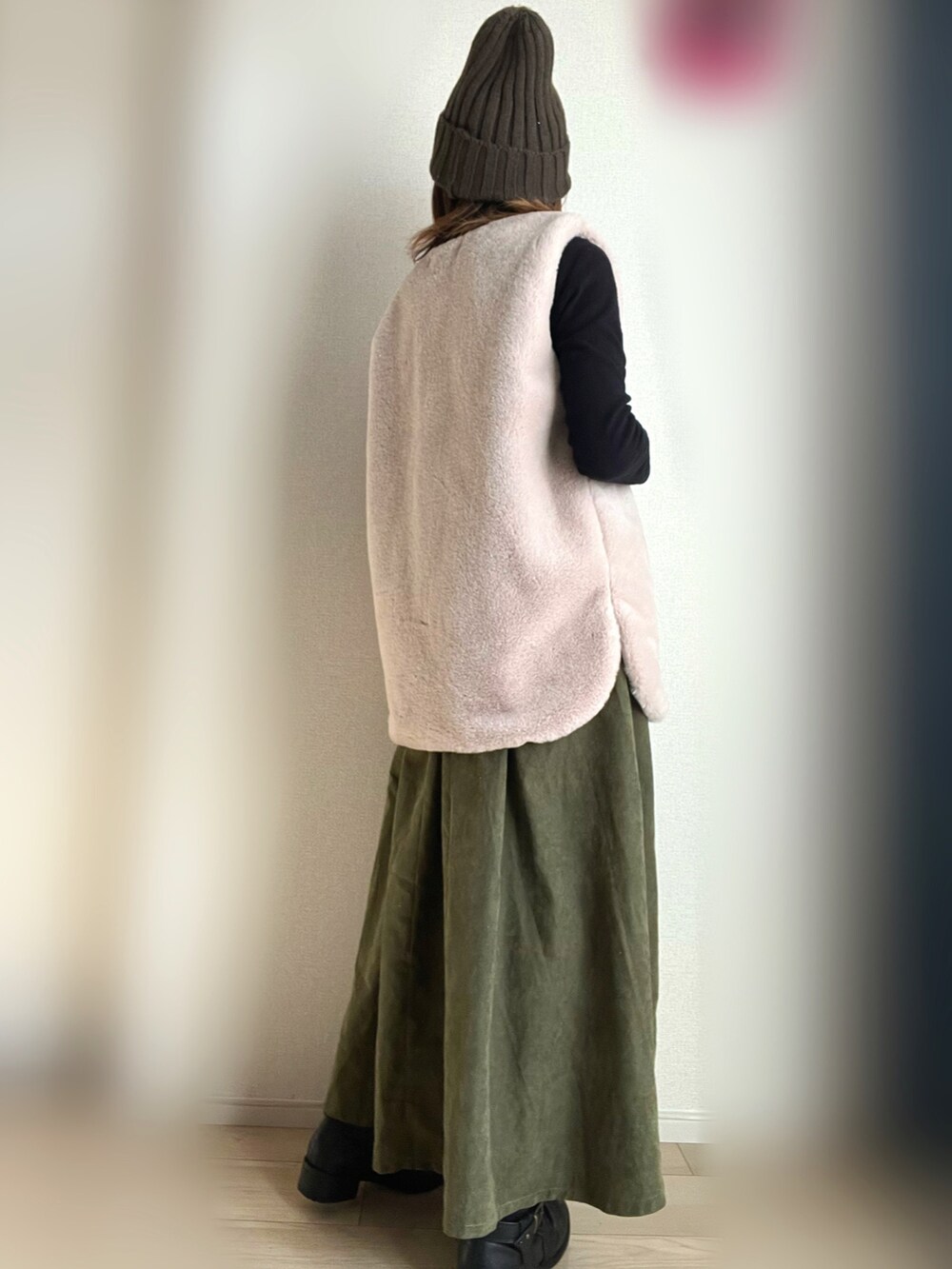 グリーン系のジャンパースカート、ベージュ系のベストを着用したレディースの冬コーディネートの3枚目の写真