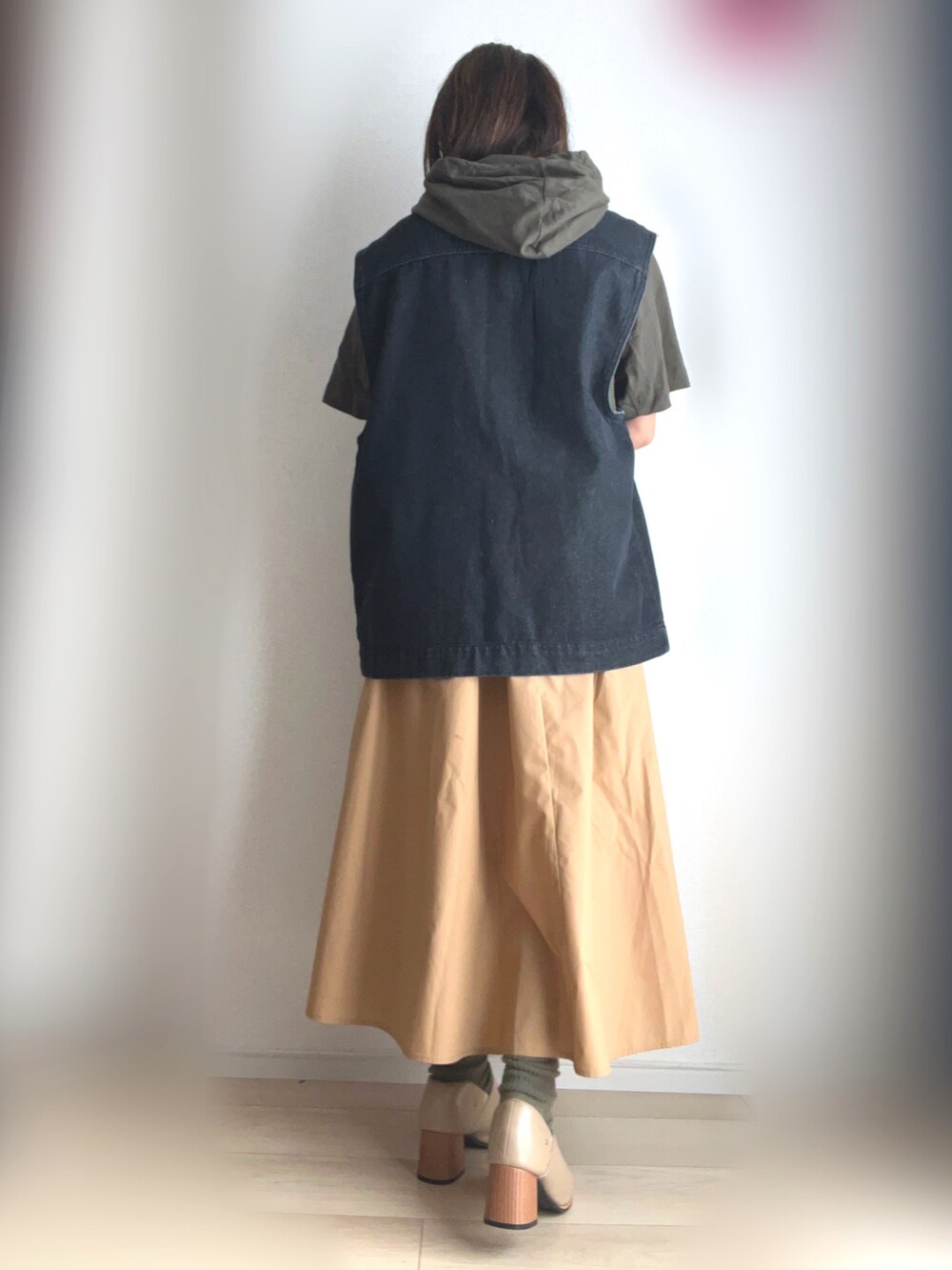 グリーン系のTシャツ/カットソー、ブラック系のベスト、ベージュ系のスカートを着用したレディースの秋コーディネートの3枚目の写真