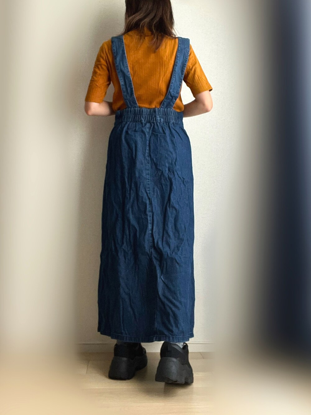 ブルー系のジャンパースカート、ブラック系のスニーカーを着用したレディースの秋コーディネートの4枚目の写真