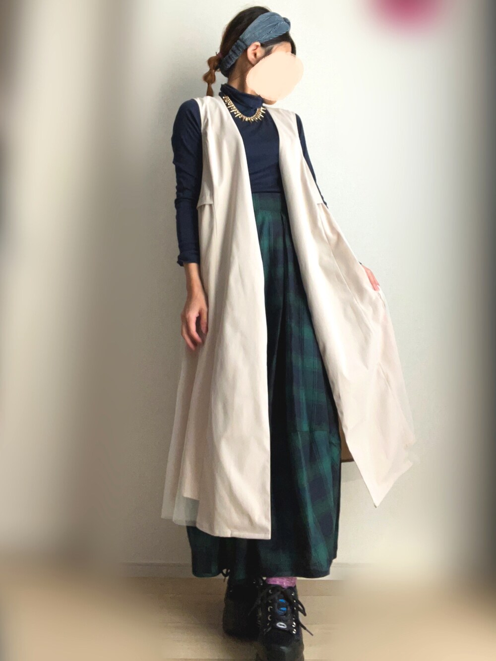 ベージュ系のベスト、グリーン系のスカート、ブラック系のスニーカーを着用したレディースの冬コーディネートの2枚目の写真