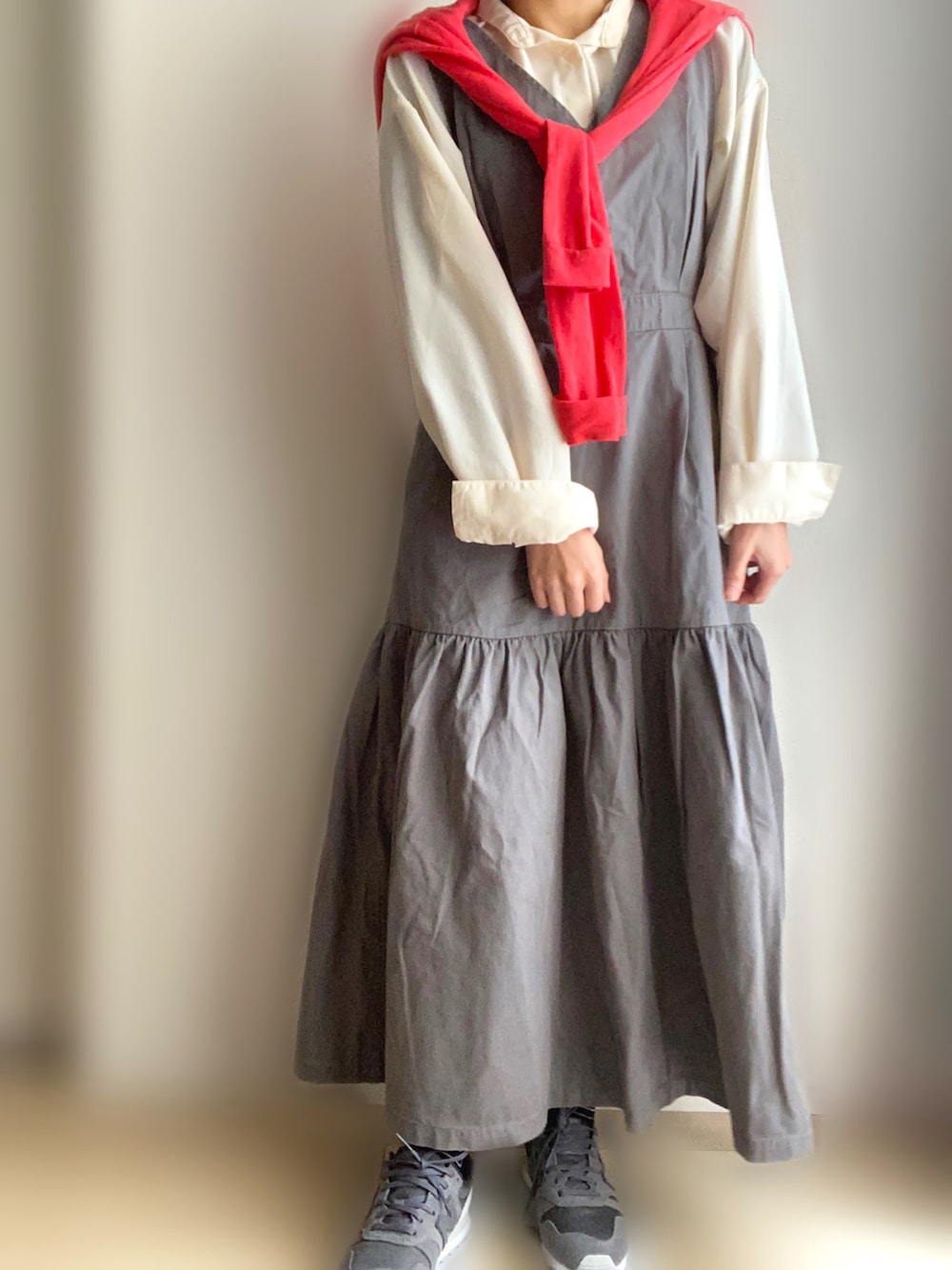 グレー系のジャンパースカート、ホワイト系のシャツ/ブラウス、グレー系のスニーカーを着用したレディースの春コーディネートの2枚目の写真