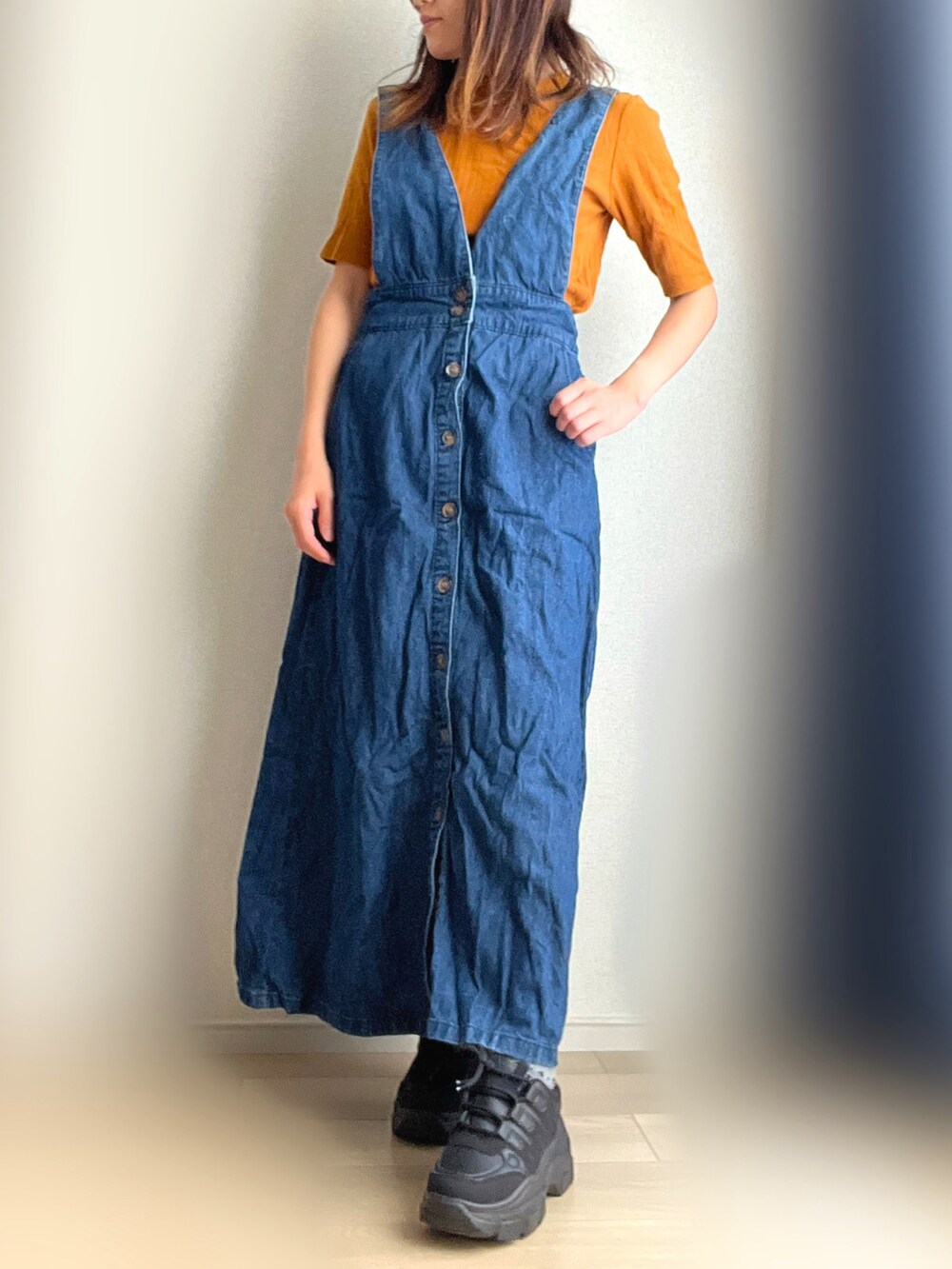 ブルー系のジャンパースカート、ブラック系のスニーカーを着用したレディースの秋コーディネートの2枚目の写真